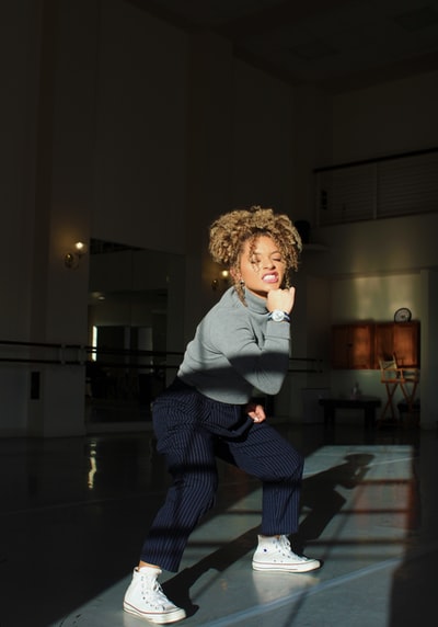 穿着灰色高领毛衣和细条纹裤蹲着的女人